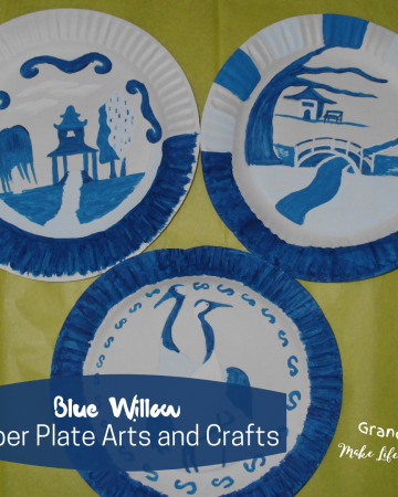 Paper plates that have been painted with blue paint to show cranes, bridges,buildings,and landscape.