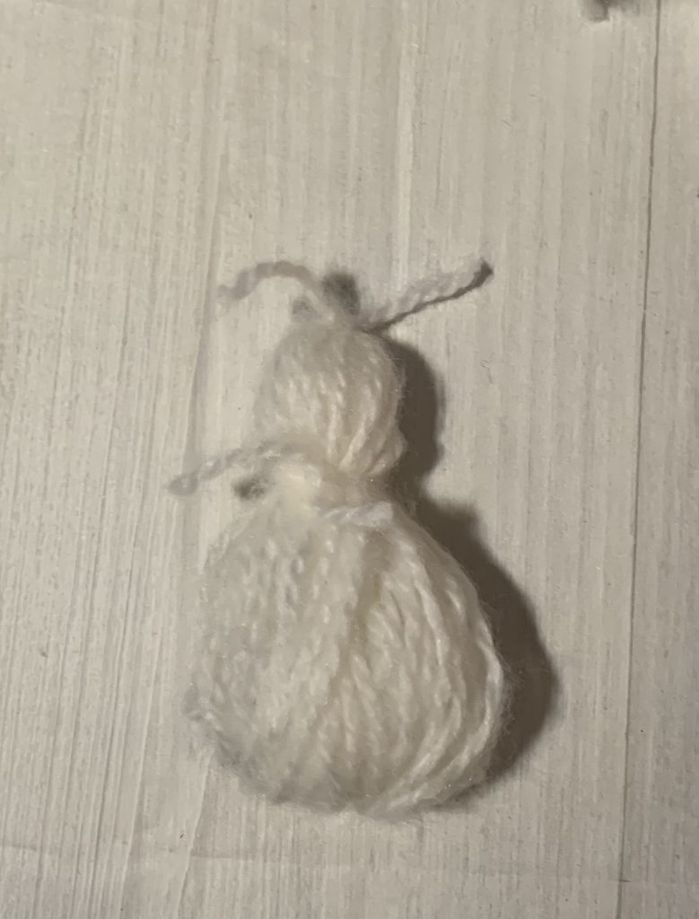 White yarn folded and made to look like a snowman.