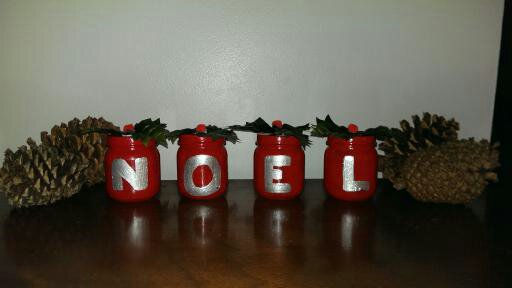 Jars painted red and the words noel written on each jar with some plastic holly on top.