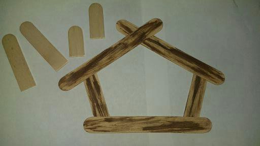 Using wood looking popsicle sticks pieced together to make a house looking structure.