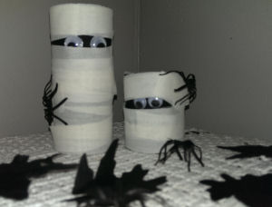 Two mummies made out of toilet paper surrounded by spiders
