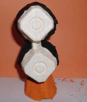 Gluing egg carton pieces together to make penguin craft body
