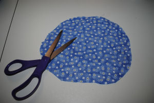 homemade pincushion made from fabric, detergent lid, and a styrofoam ball