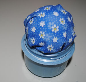 homemade pincushion made from fabric, detergent lid, and a styrofoam ball